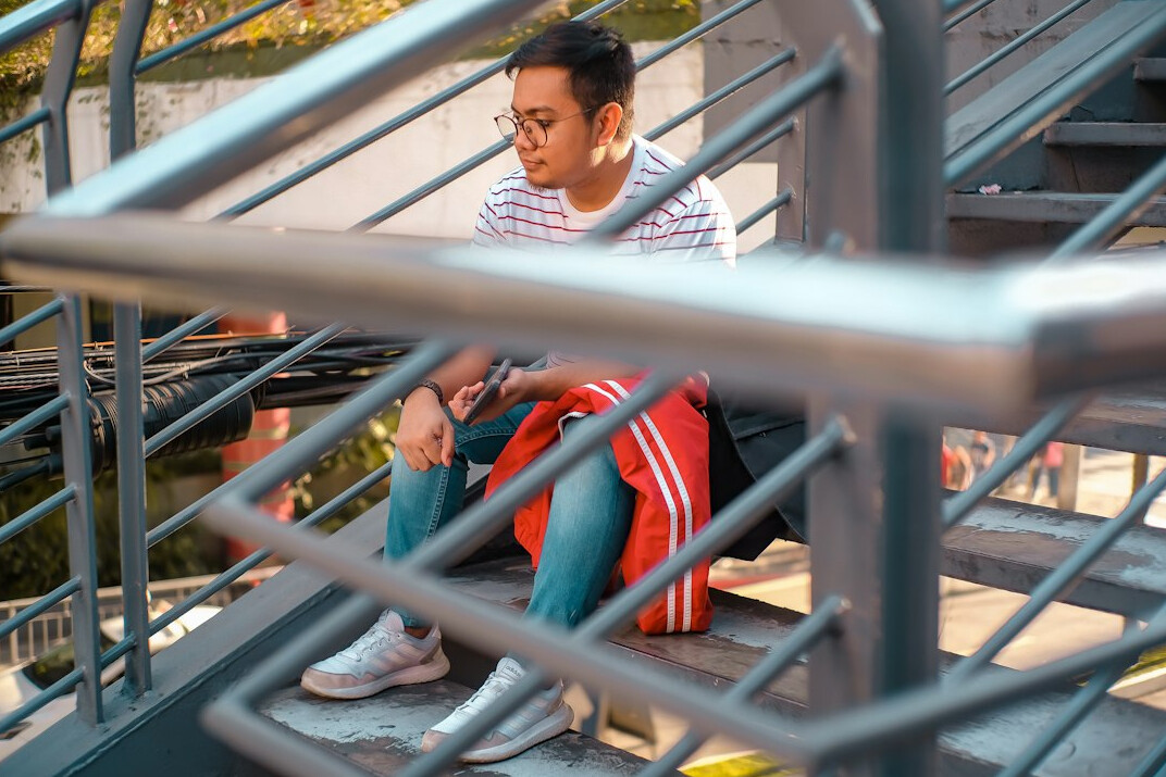 Young man reading a research report outdoors on steps